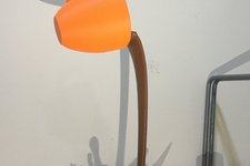 3D-Druck Symbolbild: orangene Tasse die braune Flüssigkeit ausschüttet, vor hellem Hintergrund